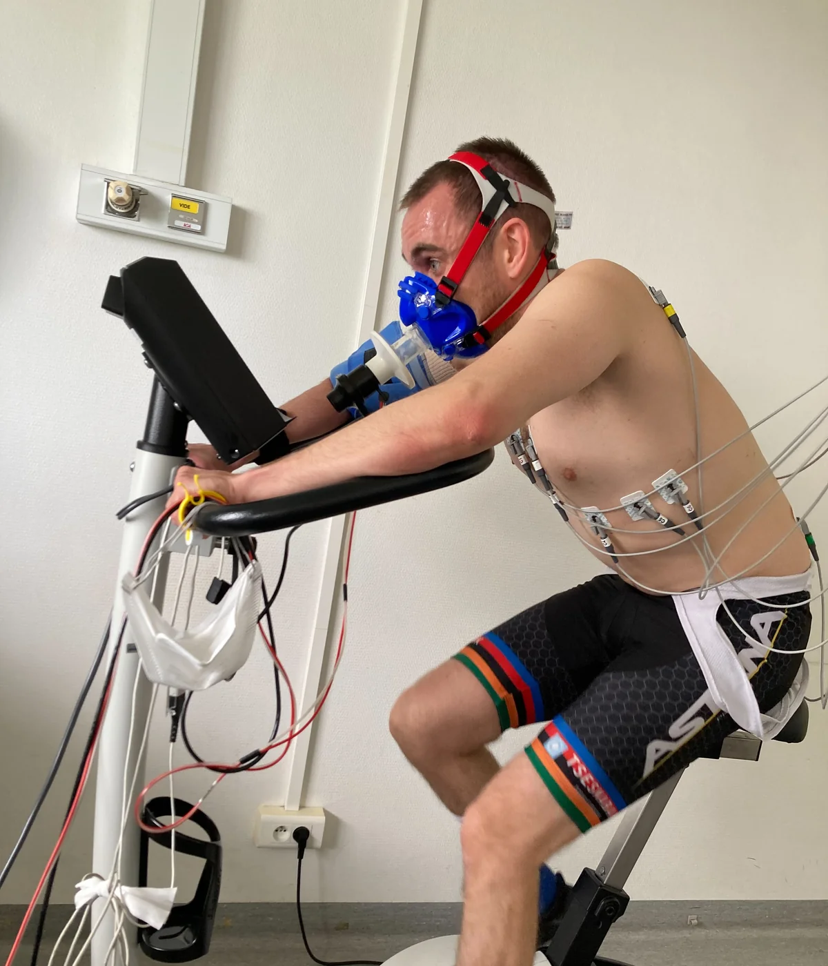 Beispiel einer Spiroergometrie: Ein Erwachsener fährt mit Atemmaske und EKG-Elektroden auf einem Fahrradergometer.